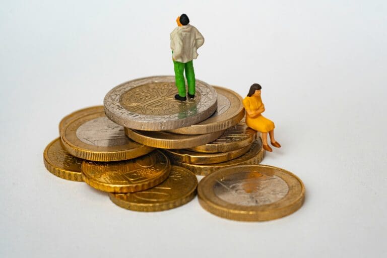 Mini couple figurine standing on coins, representing engaged couples budgeting for their wedding