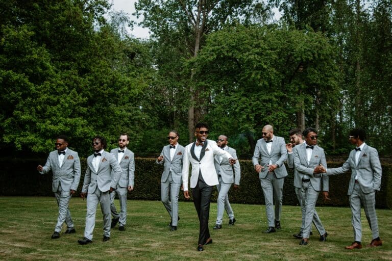Groomsmen wearing matching suits in a green outdoor setting, illustrating coordinated wedding party attire
