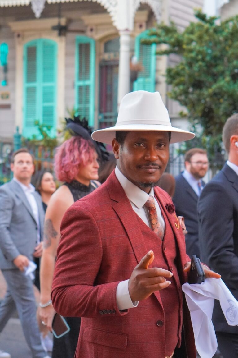 Wedding guest dressed elegantly in a red suit and white hat, illustrating stylish attire for wedding guests
