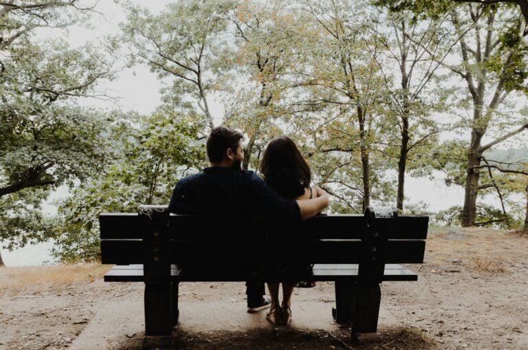 Couple communicating on a park bench, representing healthy conversations during wedding planning.