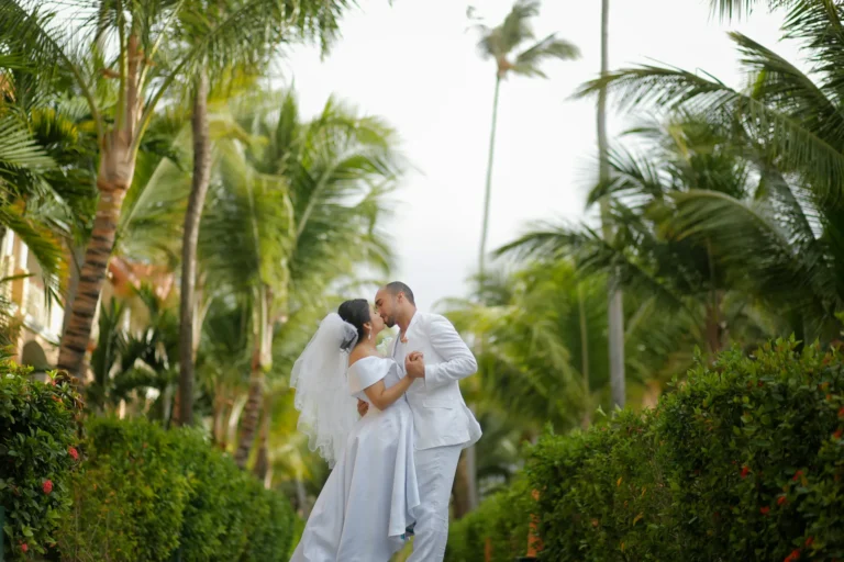 Bride and groom kissing at tropical destination wedding under palm trees – romantic destination wedding